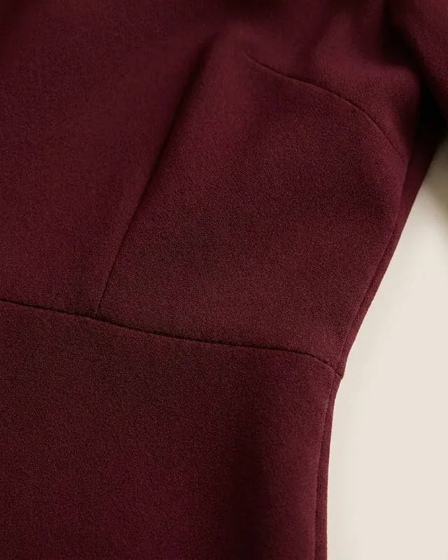 Gros plan sur le crêpe mat et la couture à la taille de la Robe Midi Bordeaux